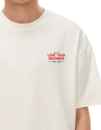 White t-shirt with red text saying told to love your neighbor on a white background