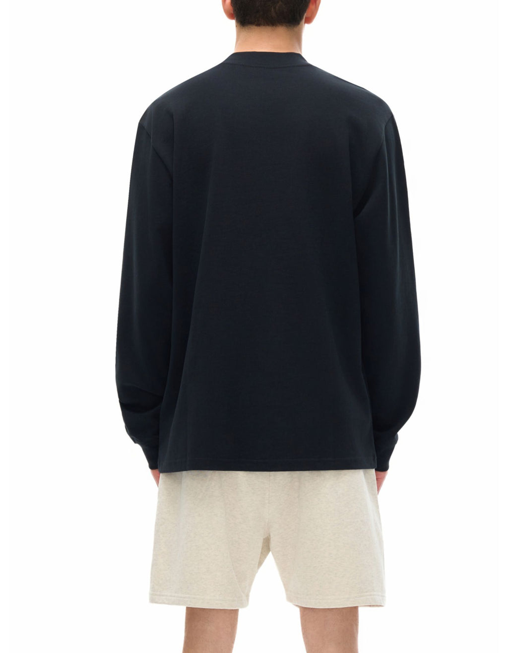 Person wearing a black long sleeve t-shirt and beige shorts on a white background