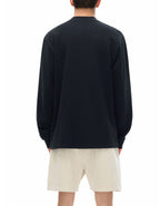 Person wearing a black long sleeve t-shirt and beige shorts on a white background