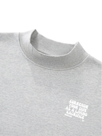 Close-up of a light heather gray crewneck sweatshirt with a small white graphic text on the left chest reading 'SURRENDER YOUR LIFE AS A LIVING SACRIFICE' and 'ROMANS 12' below it.
