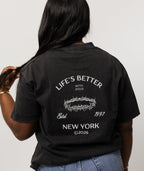 A woman viewed from behind wearing a black graphic T-shirt stating life's better with jesus with white text and a crown of thorns design on the back